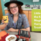 Photo of staff member Jill holding a cup with a pumpkin face on it and sitting at a table that is adorned with orange and red leaf placemats, a plate of "magic wand" choocolate covered pretzel rods, and a stack of creepy books Halloween decor.