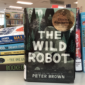 Photo of new Wonderbook type book spines and cover of The Wild Robot by Peter Brown