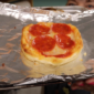 Photo of a small pepperoni pizza on a sheet pan covered in foil.