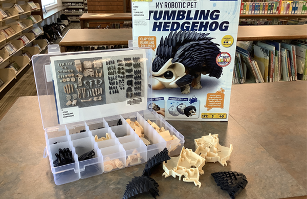 Photo of the Tumbling Hedgehog STEM Kit contents, displayed on the top of a shelf, including a divided cases of small pieces and larger pieces of the hedgehog body.